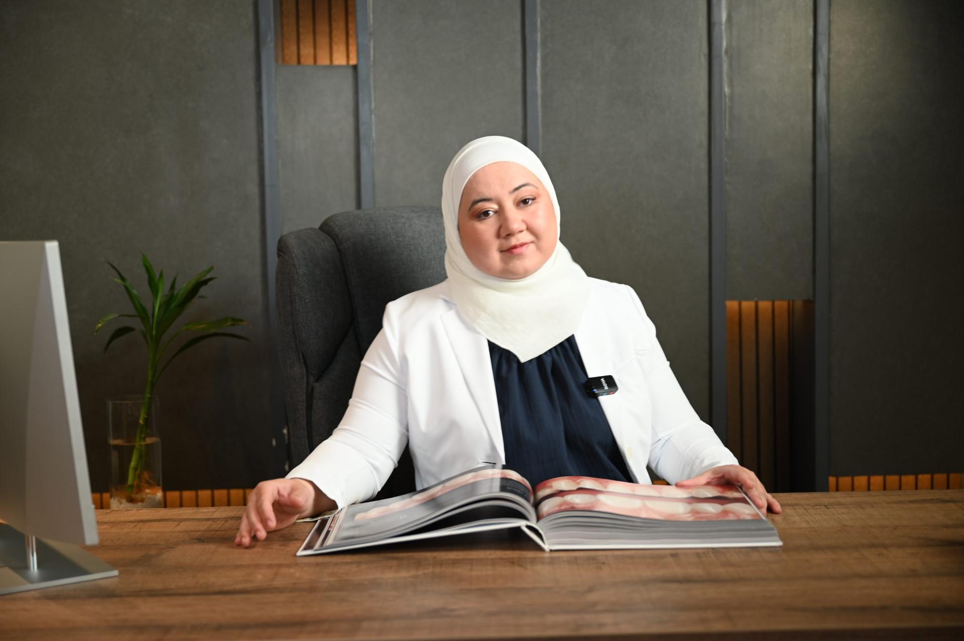 د. دانا أبوروائح إلى مكتبها وأمامها أطلس مفتوح